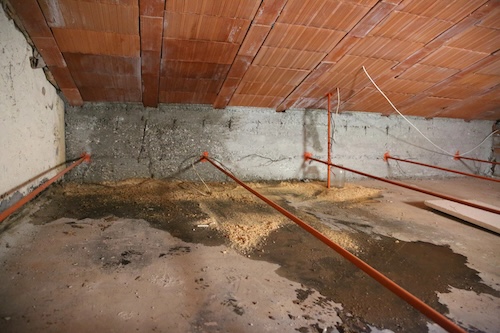 wet spots in the attic from water seeping from a broken red orange roof