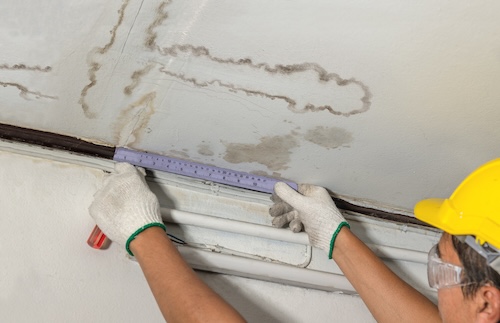 water damage expert measuring water stains on ceiling