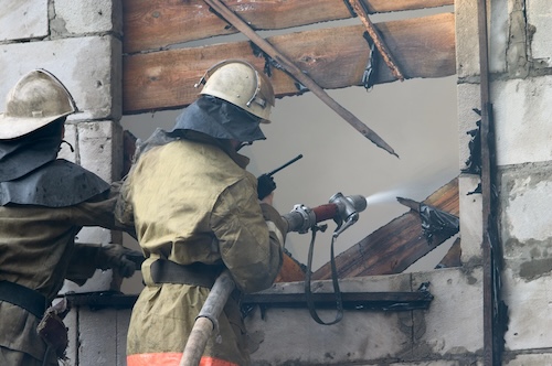 firefighter spraying water into burned window