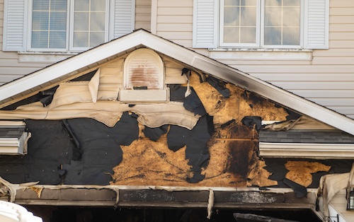 A close-up view of a neighborhood garage roof, which bears the scars of recent accidental fire damage